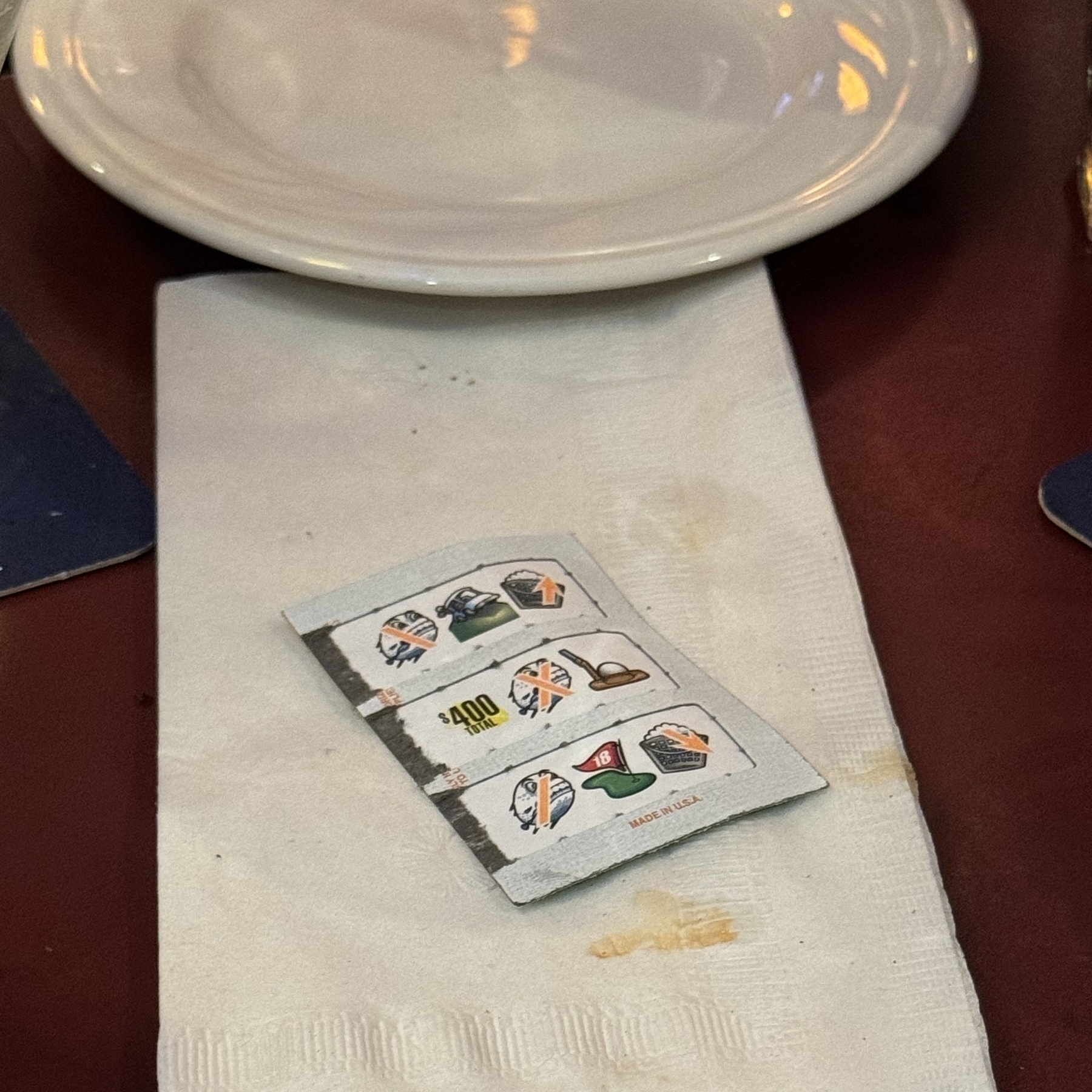 Auto-generated description: A napkin with a winning pull tab for $400 placed on a table next to a white plate.